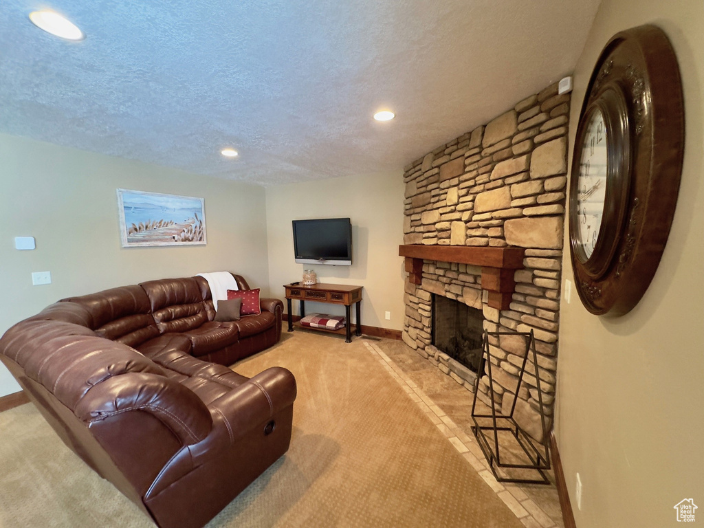 Carpeted living room with a textured ceiling and a stone fireplace