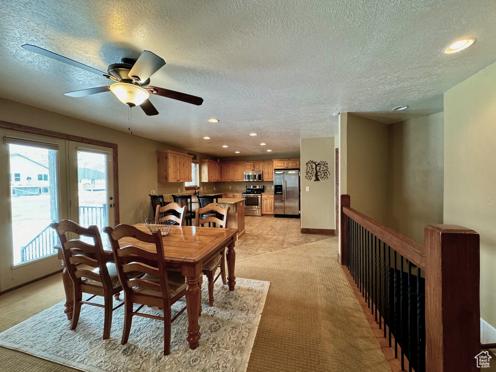 Carpeted dining space featuring ceiling fan and a textured ceiling