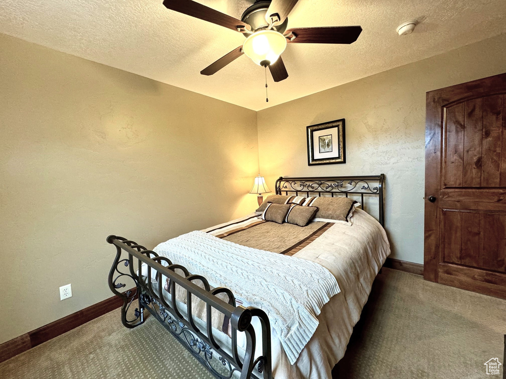 Carpeted bedroom with a textured ceiling and ceiling fan