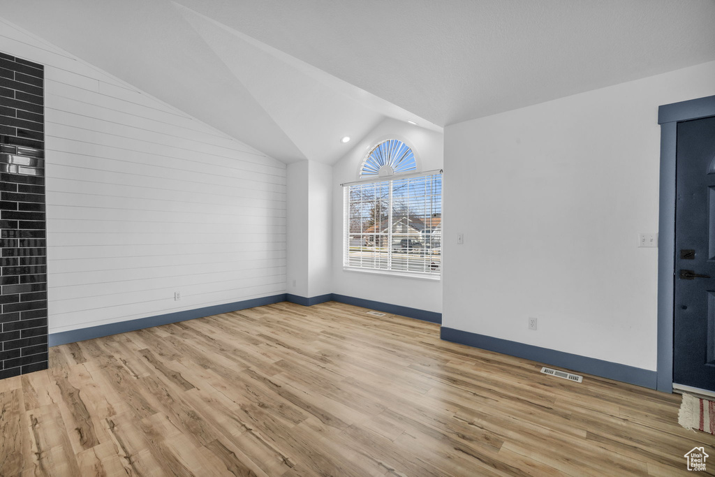 Unfurnished room with vaulted ceiling and light hardwood / wood-style floors