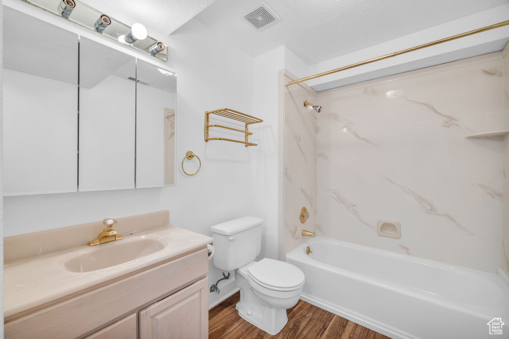 Full bathroom with shower / bath combination, vanity, wood-type flooring, and toilet