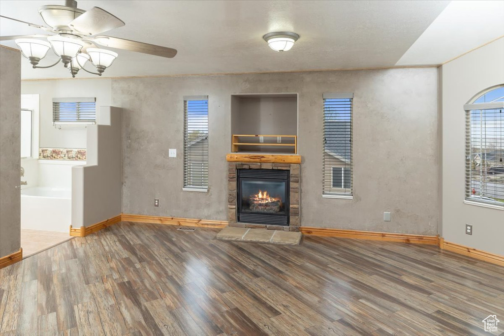 Unfurnished living room with dark hardwood / wood-style floors, ceiling fan, and a fireplace