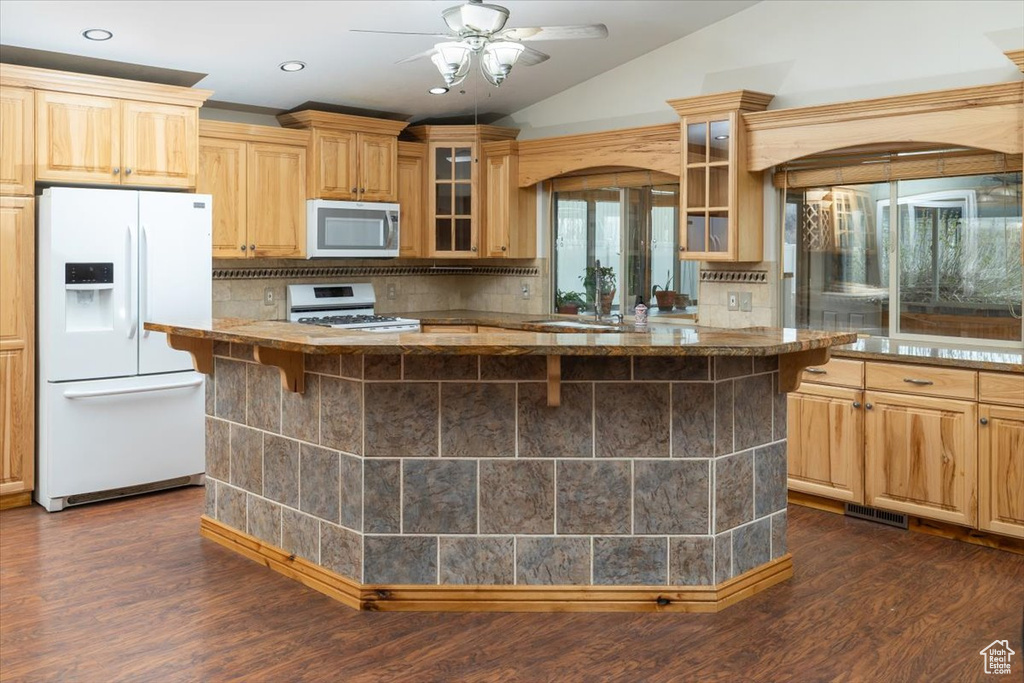 Kitchen with a kitchen breakfast bar, ceiling fan, tasteful backsplash, dark wood-type flooring, and white appliances