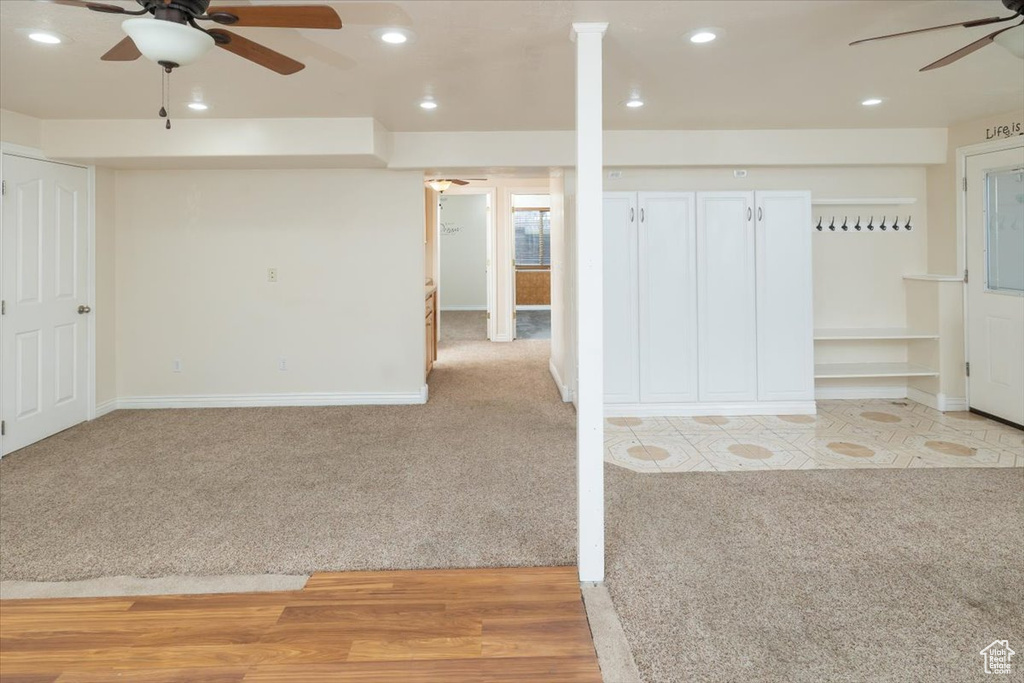 Basement with light carpet and ceiling fan