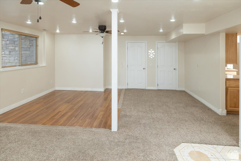 Basement with ceiling fan and light hardwood / wood-style flooring