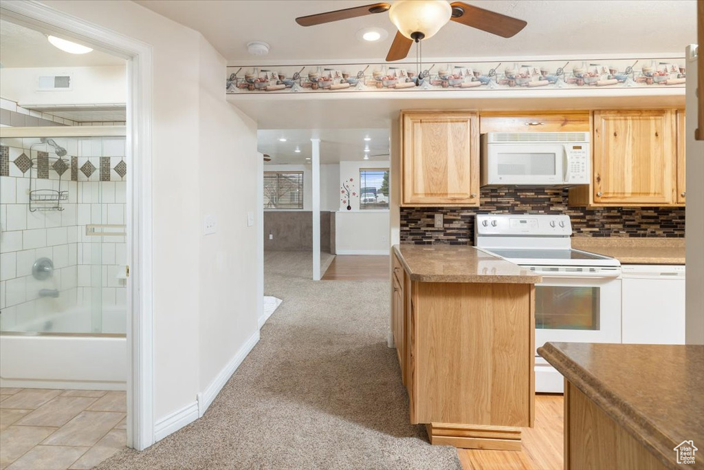 Kitchen featuring light brown cabinets, light tile floors, ceiling fan, white appliances, and backsplash