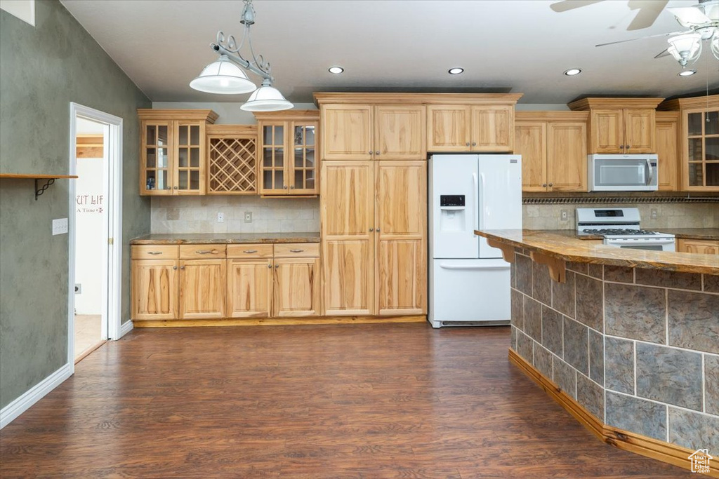 Kitchen with white appliances, ceiling fan, backsplash, and dark wood-type flooring
