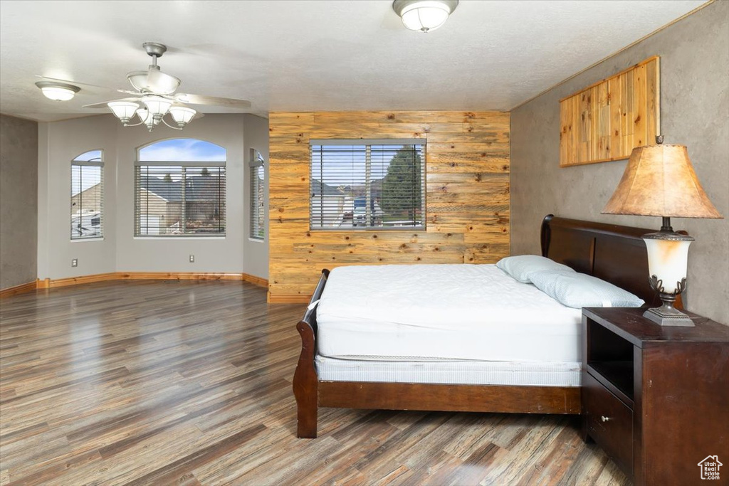 Bedroom with wooden walls, ceiling fan, and dark hardwood / wood-style flooring