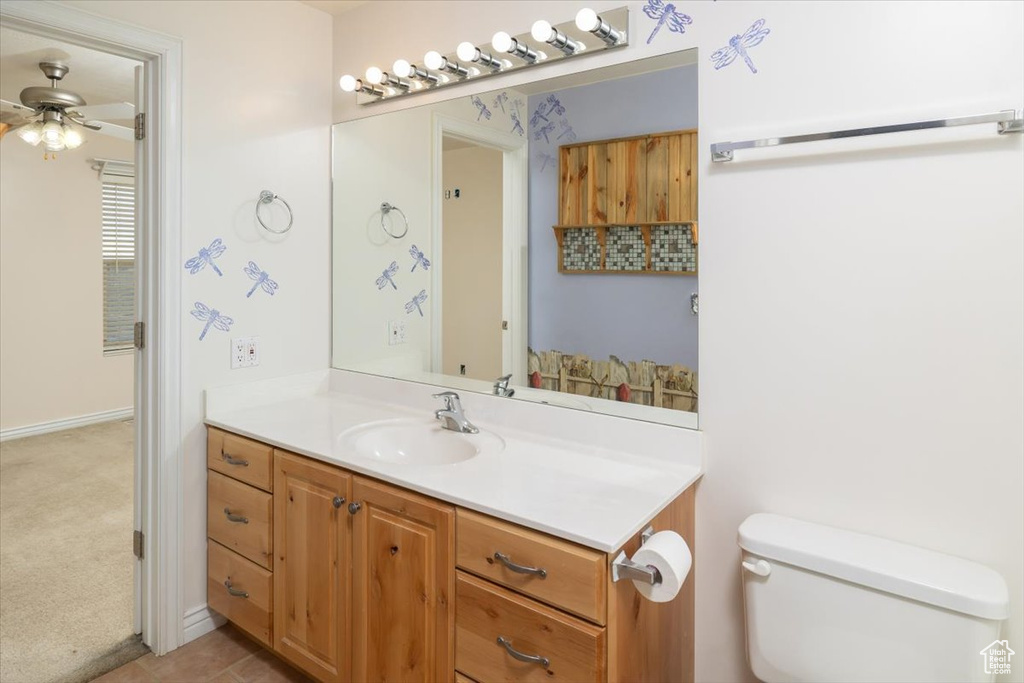 Bathroom featuring toilet, tile floors, ceiling fan, and vanity