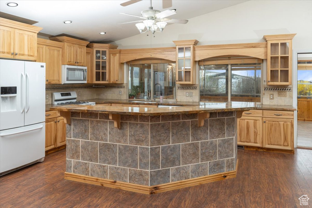 Kitchen with dark hardwood / wood-style floors, white appliances, ceiling fan, backsplash, and vaulted ceiling