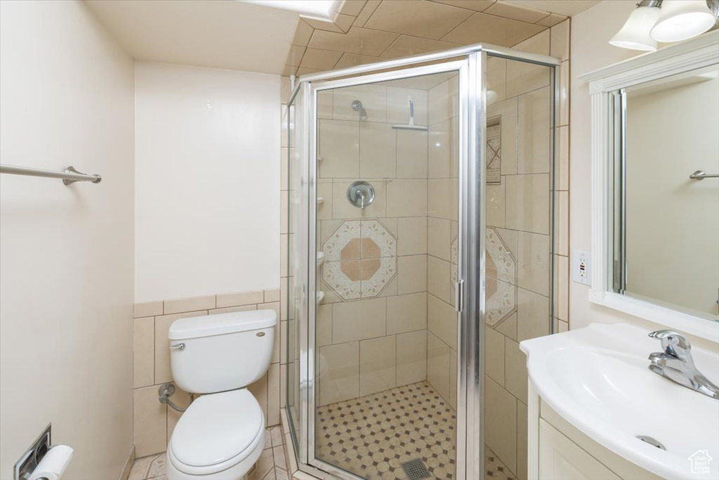 Bathroom featuring tile walls, walk in shower, toilet, tile floors, and large vanity