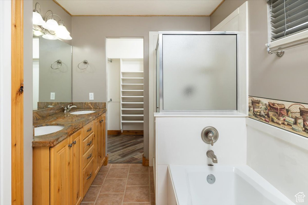 Bathroom featuring tile floors, dual bowl vanity, and a bathing tub