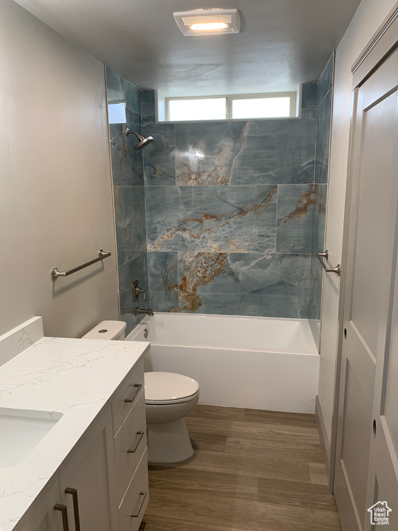 Full bathroom featuring hardwood / wood-style floors, toilet, vanity, and tiled shower / bath