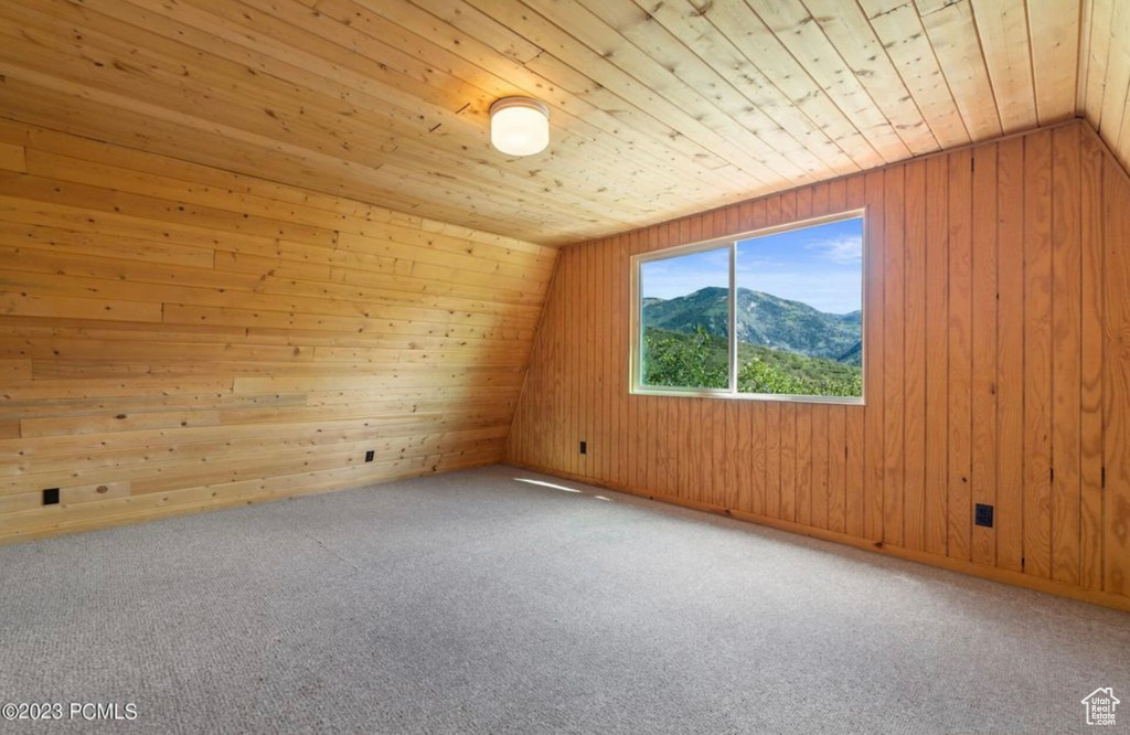 Additional living space with lofted ceiling, a mountain view, wooden ceiling, and light carpet
