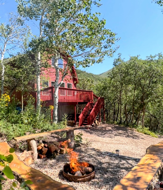 View of jungle gym with a wooden deck and an outdoor fire pit