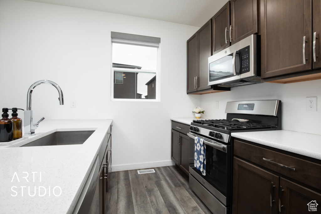 Kitchen with sink, dark brown cabinetry, dark hardwood / wood-style flooring, and stainless steel appliances