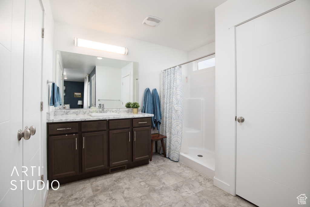 Bathroom featuring a shower with curtain, tile floors, and large vanity