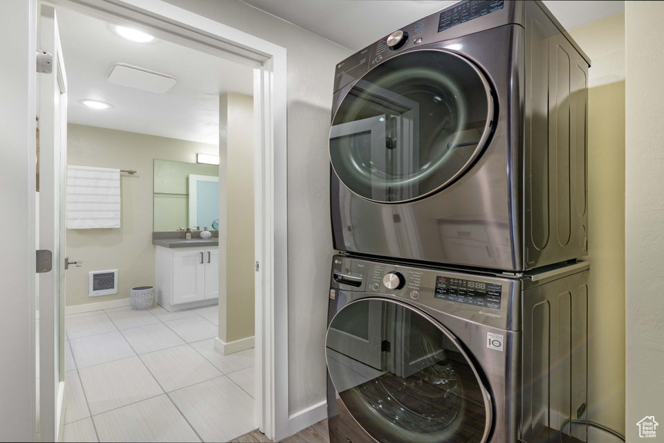 Laundry area featuring light tile floors and stacked washer and dryer