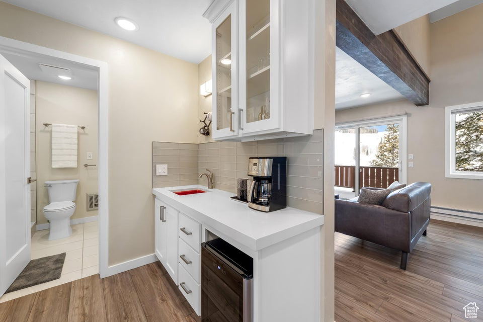 Kitchen featuring backsplash, light tile flooring, white cabinets, and sink