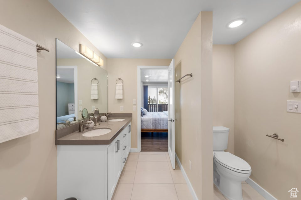 Bathroom with toilet, dual bowl vanity, and tile floors
