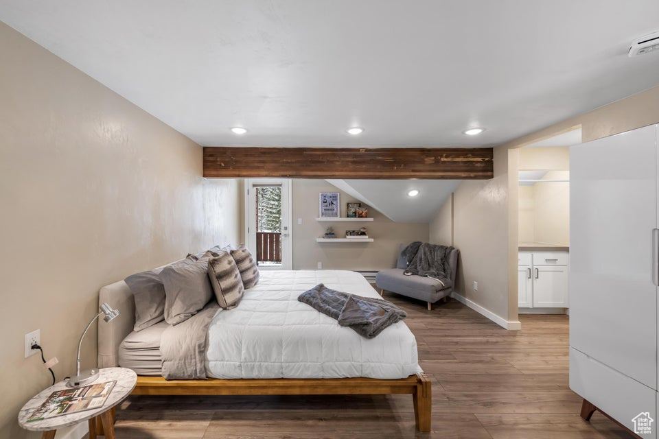 Bedroom with hardwood / wood-style floors, a baseboard heating unit, and beamed ceiling