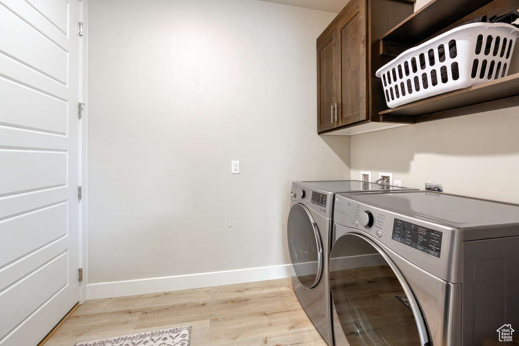 Laundry room featuring washer and clothes dryer, cabinets, washer hookup, and light hardwood / wood-style flooring