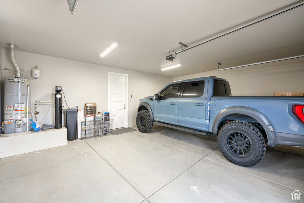 Garage featuring secured water heater and a garage door opener