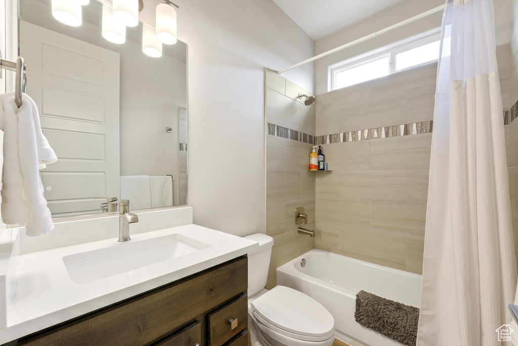 Full bathroom with shower / bath combination with curtain, large vanity, and toilet