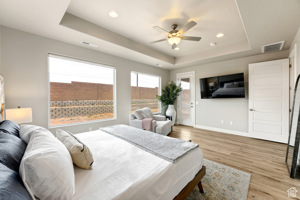 Bedroom featuring a tray ceiling, ceiling fan, and light hardwood / wood-style flooring