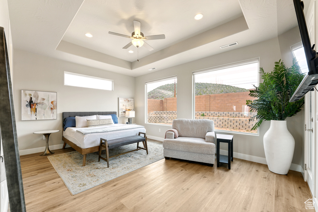 Bedroom featuring a tray ceiling, ceiling fan, and light hardwood / wood-style flooring