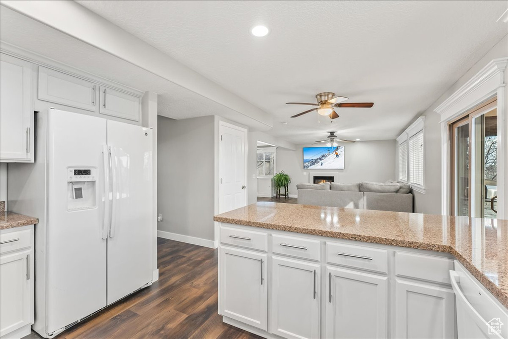 Kitchen with white cabinets, dark wood-type flooring, ceiling fan, and white appliances