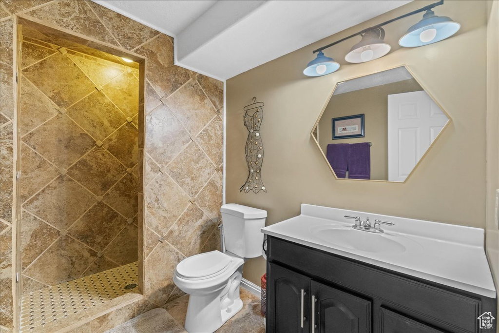 Bathroom with vanity, tile walls, tiled shower, tile flooring, and toilet