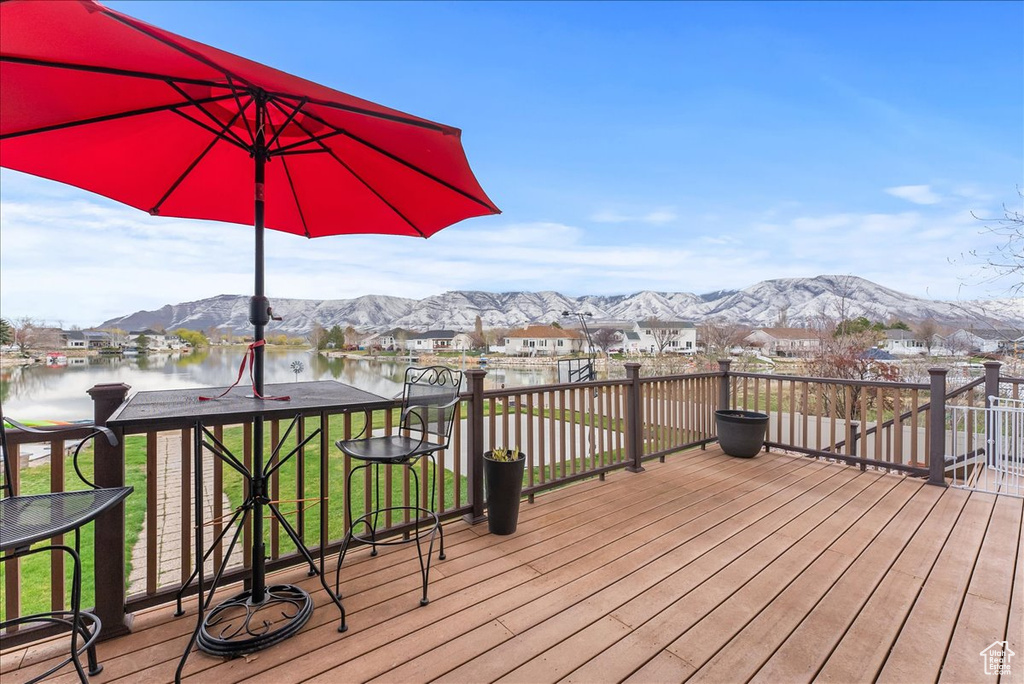 Wooden deck with a lawn and a water and mountain view