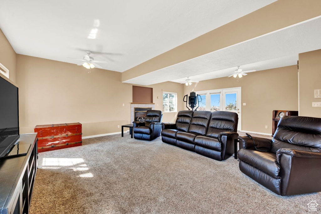 Carpeted living room featuring a tile fireplace and ceiling fan