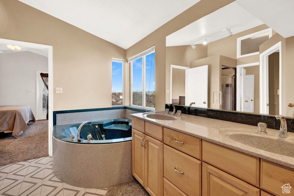 Bathroom with oversized vanity, vaulted ceiling, a bathing tub, rail lighting, and dual sinks
