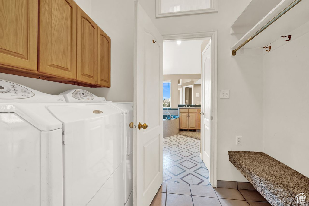 Washroom featuring cabinets, washer and dryer, and light tile floors