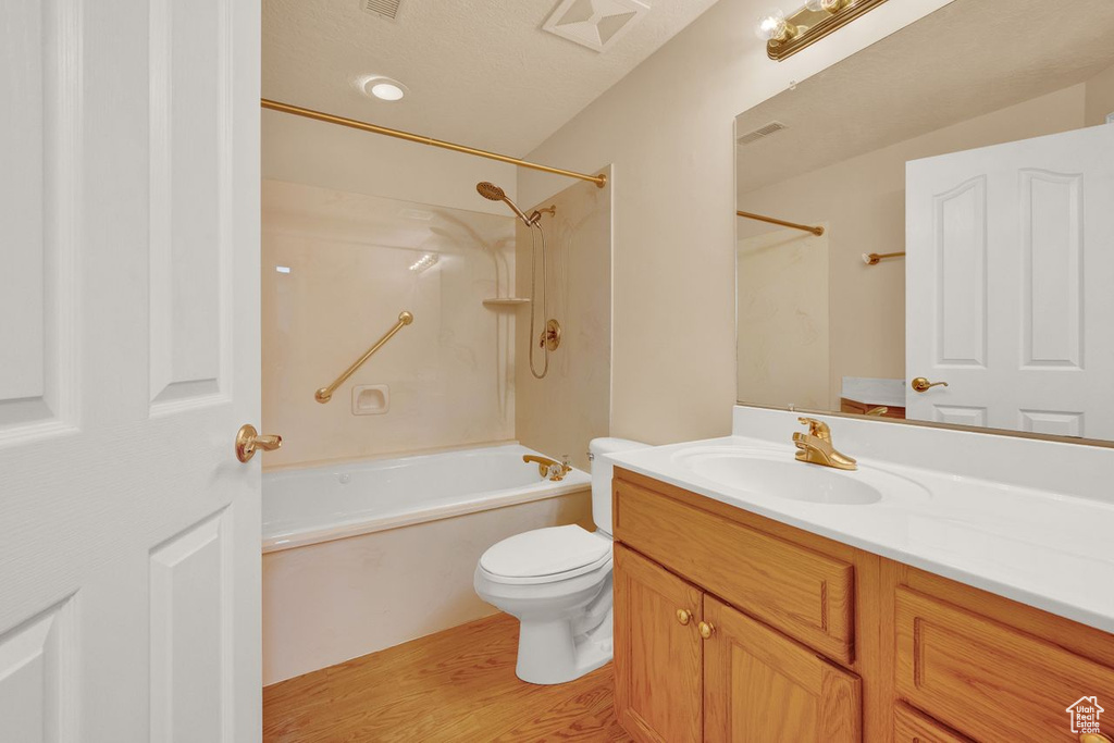 Full bathroom featuring toilet, shower / washtub combination, wood-type flooring, oversized vanity, and a textured ceiling