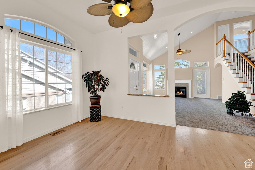 Carpeted entryway featuring plenty of natural light, ceiling fan, and high vaulted ceiling