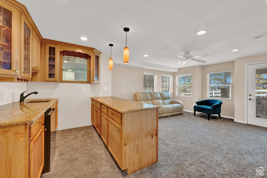 Kitchen with light colored carpet, decorative light fixtures, ceiling fan, kitchen peninsula, and sink