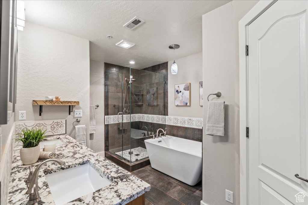 Bathroom featuring plus walk in shower, dual vanity, and a textured ceiling