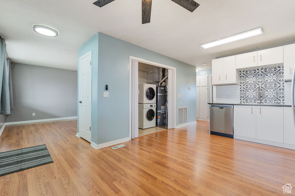 Kitchen featuring white cabinetry, backsplash, light hardwood / wood-style flooring, stacked washer and clothes dryer, and dishwasher