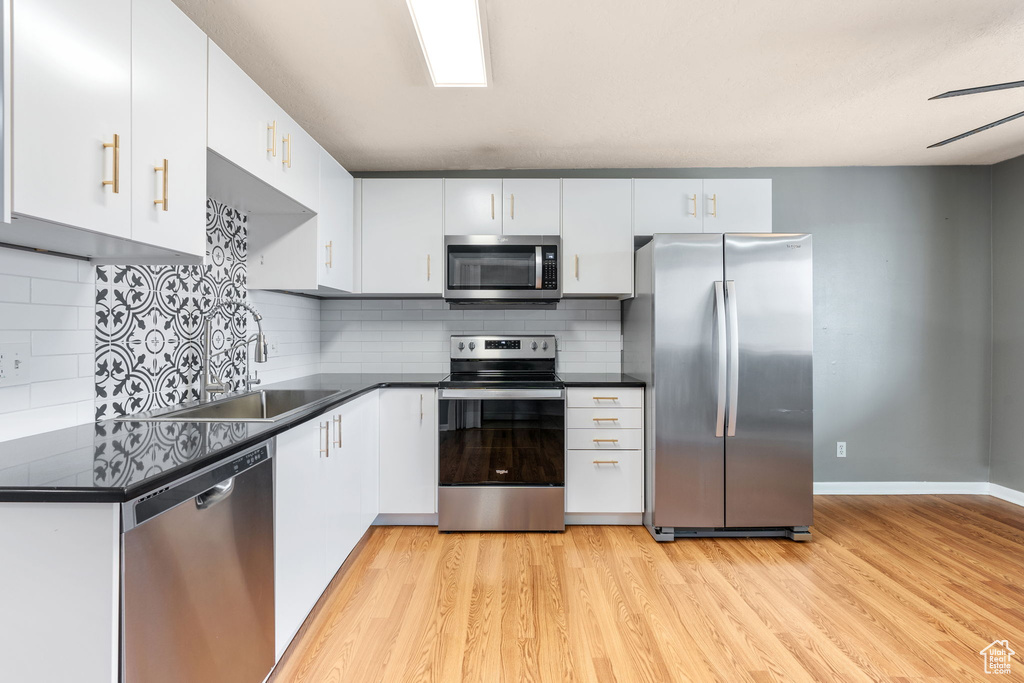 Kitchen with tasteful backsplash, light wood-type flooring, and stainless steel appliances