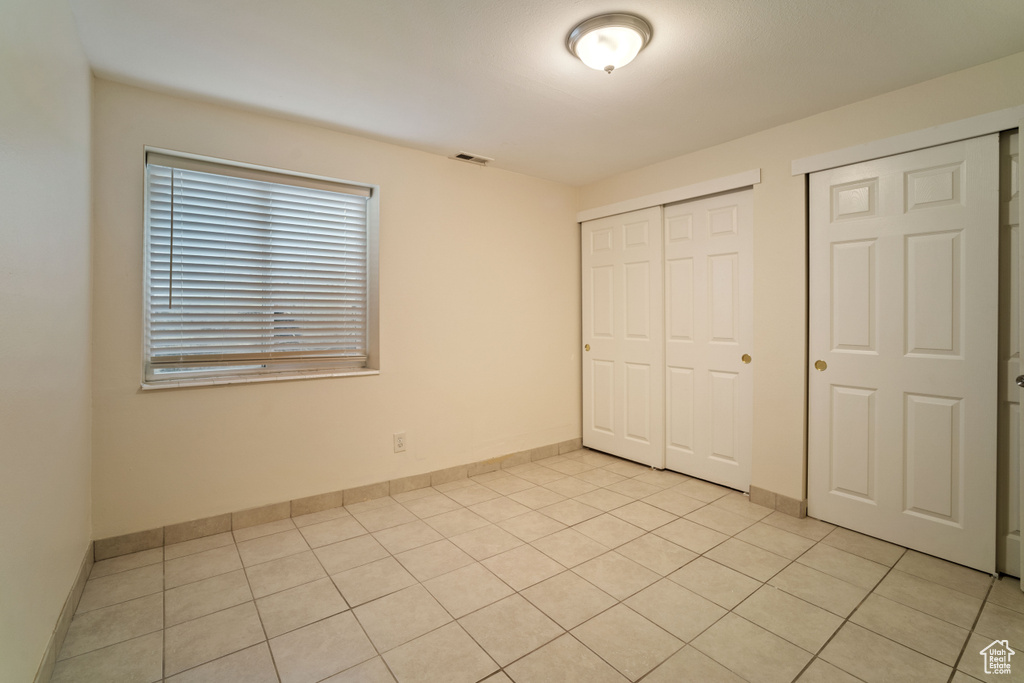 Unfurnished bedroom featuring light tile floors and two closets