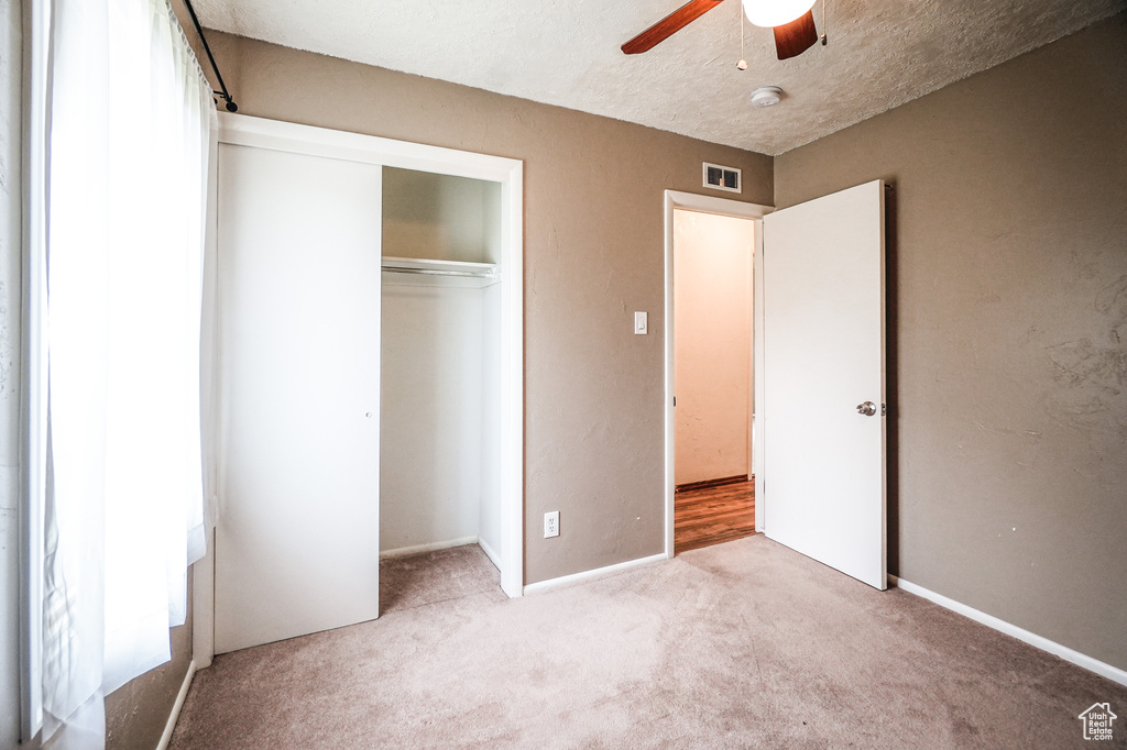 Unfurnished bedroom featuring a textured ceiling, a closet, ceiling fan, and light hardwood / wood-style flooring