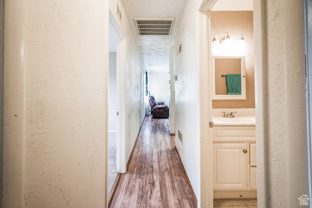 Corridor with hardwood / wood-style flooring, a textured ceiling, and sink