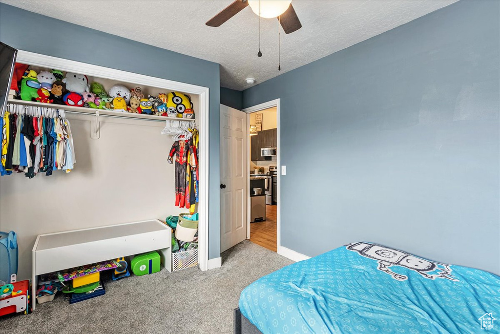 Bedroom featuring a closet, a textured ceiling, ceiling fan, and light colored carpet
