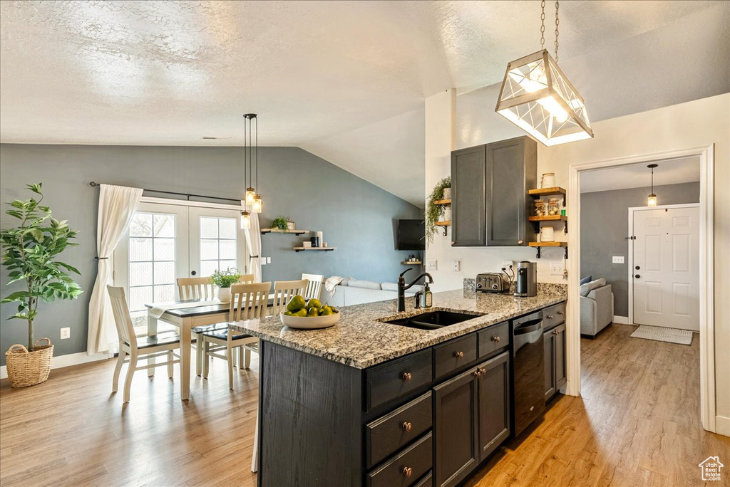 Kitchen with pendant lighting, light stone countertops, light hardwood / wood-style floors, and sink