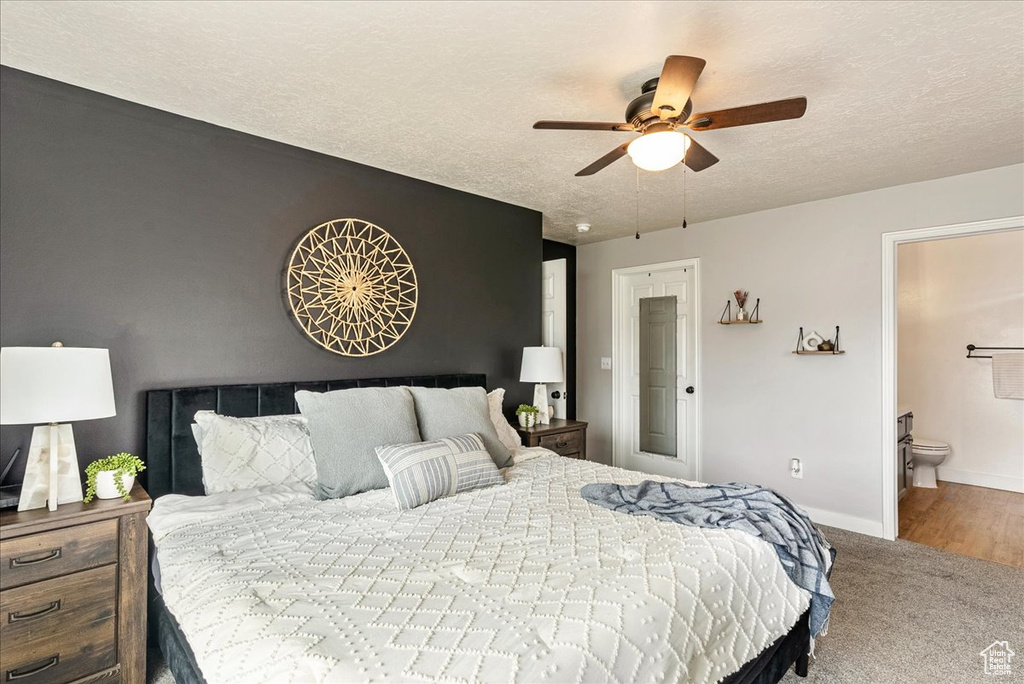 Bedroom featuring hardwood / wood-style floors, ensuite bath, ceiling fan, and a textured ceiling