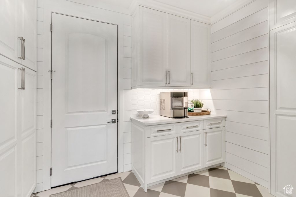 Laundry room featuring crown molding and light tile floors