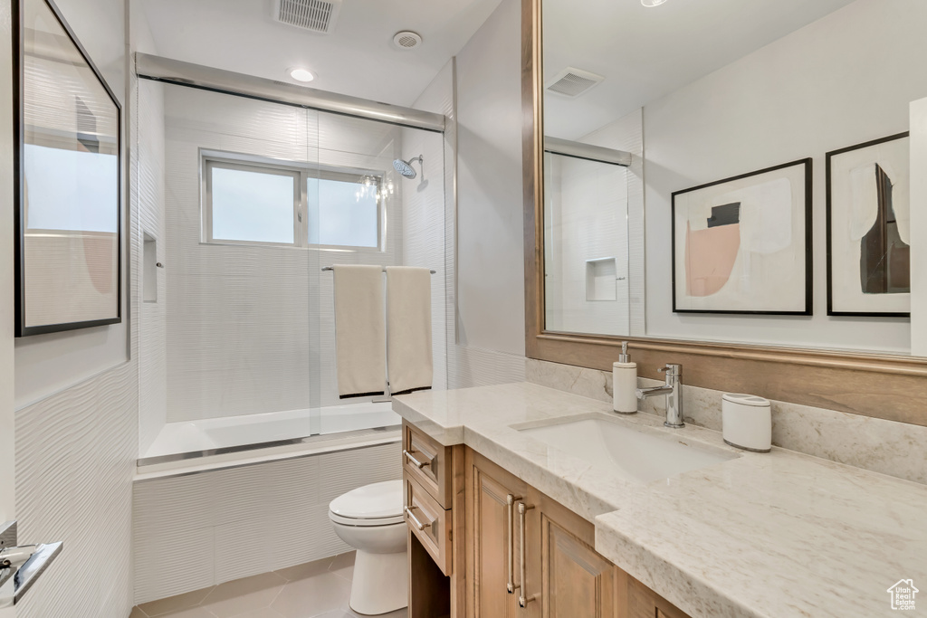 Full bathroom with vanity, tile flooring, bath / shower combo with glass door, and toilet